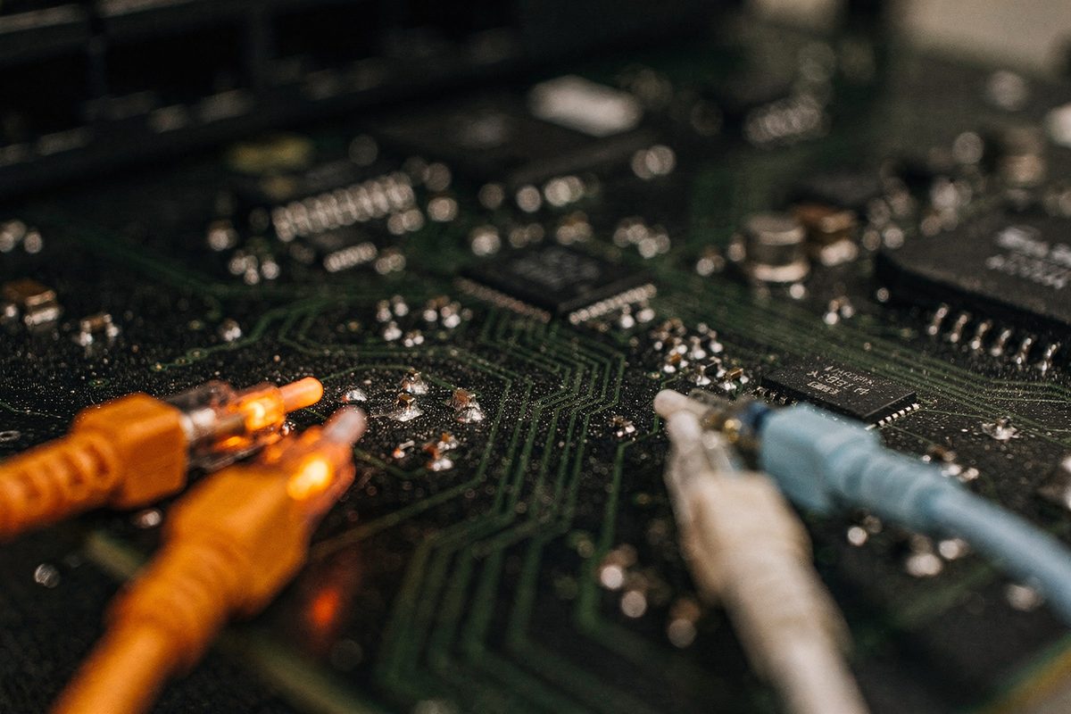 A macro photograph of a circuit board and glowing fibre-optic cable ends