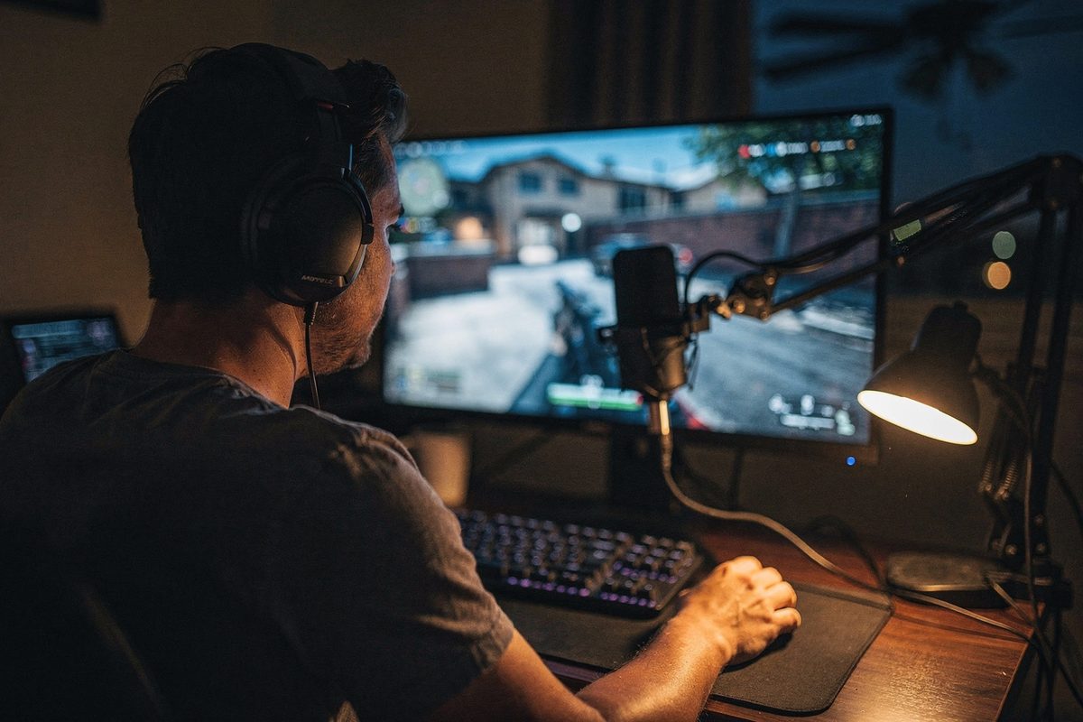 A gamer at a night battlestation wearing a headset with a boom microphone in frame